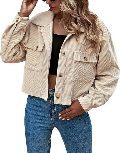 Woman in a cropped beige jacket and black top, wearing blue jeans.